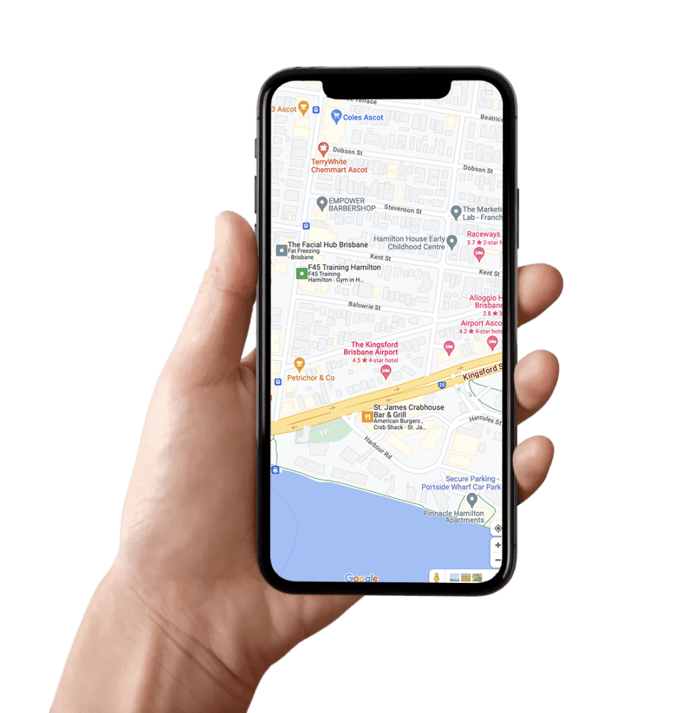 A hand is holding a smartphone displaying a map with streets, locations, and landmarks near the coast, including restaurants, educational centers, and IV Infusion Therapy Brisbane clinics on the screen.